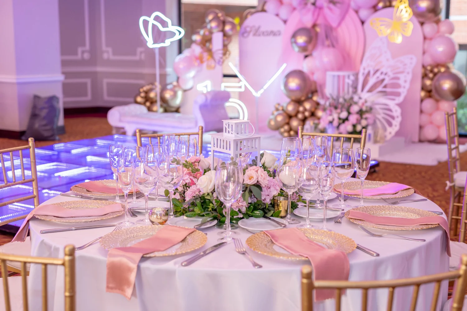 Montaje elegante para celebración social de 15 años con mesa decorada en tonos rosa y dorado